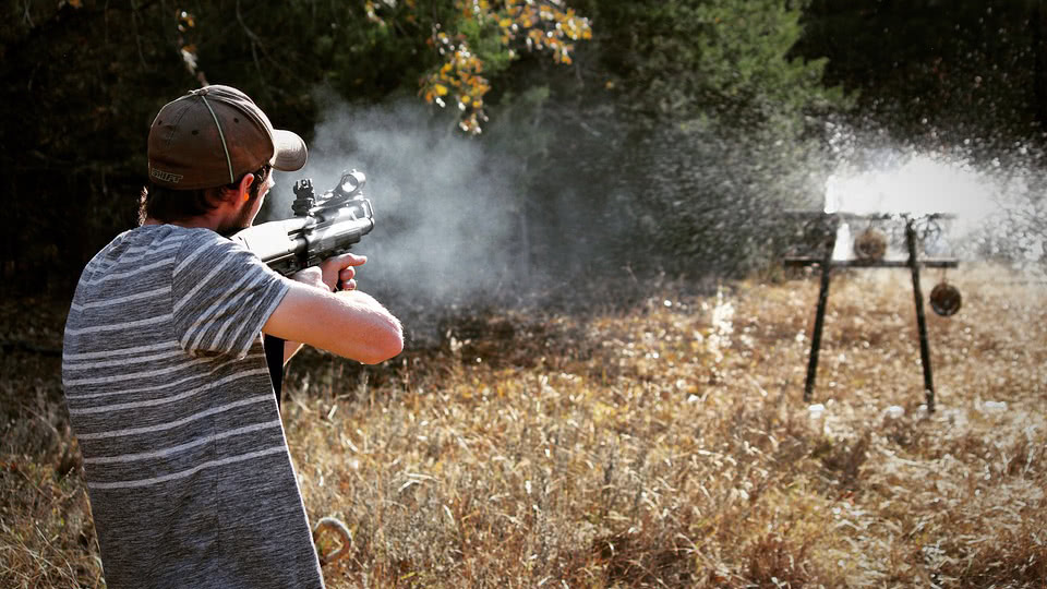 Man shooting at a target from assault rifle in the backyard